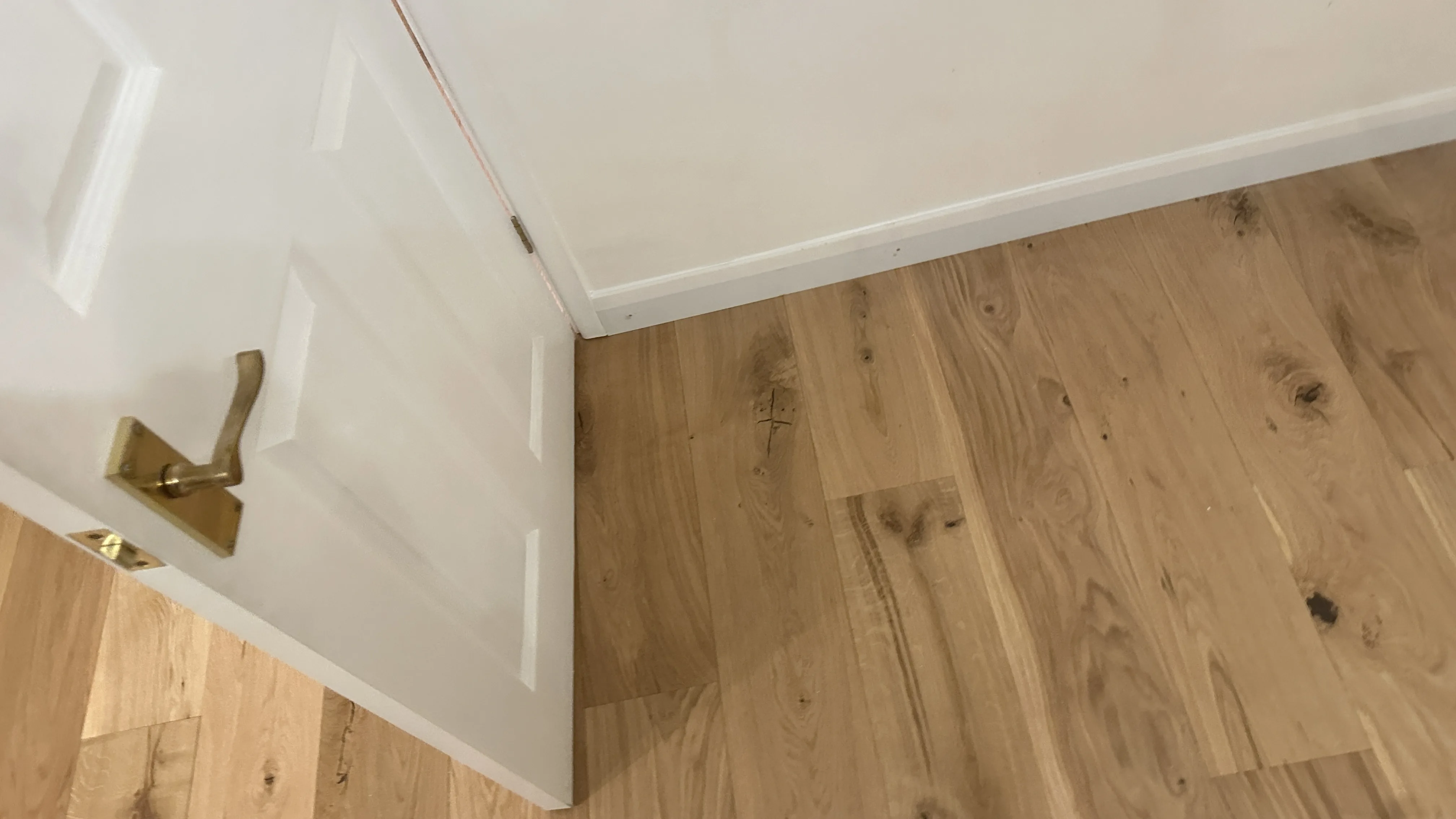 Flooring Installation project in Bicester - a white door with a wooden floor and a white wall